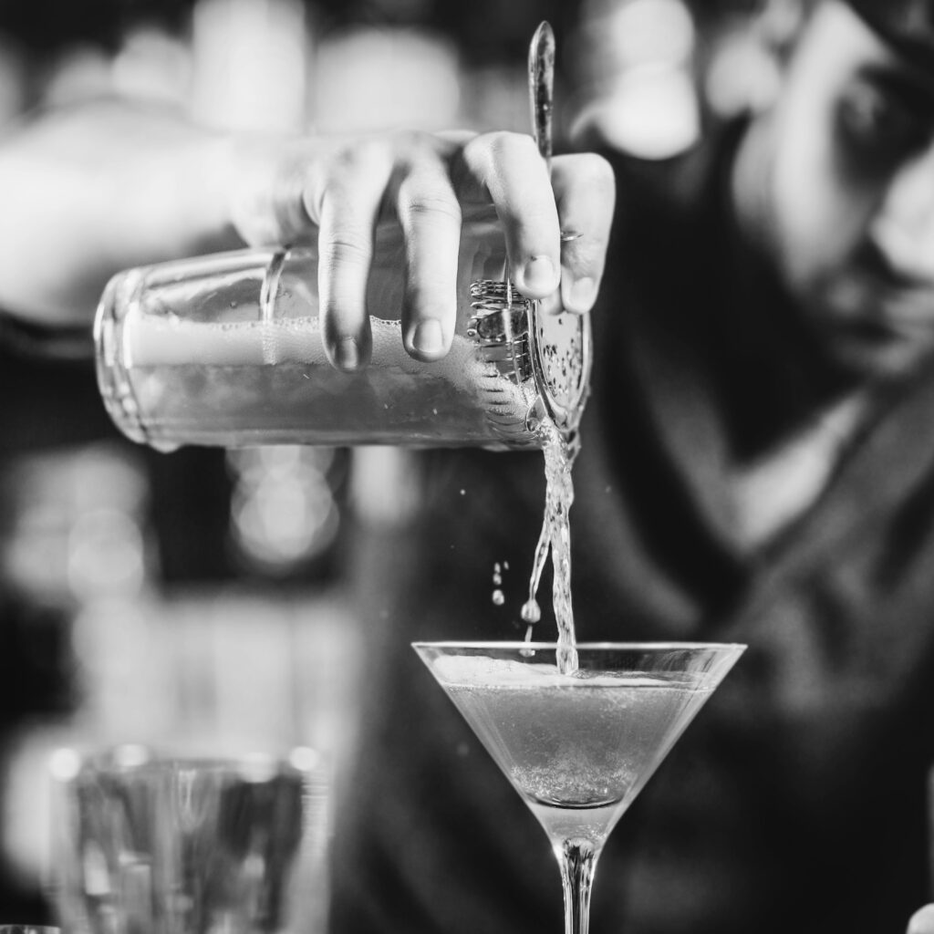 Barman sirviendo un cóctel en copa martini.
